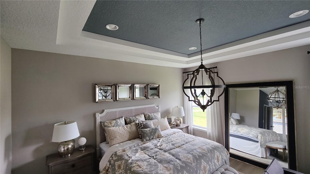 bedroom with a tray ceiling, a textured ceiling, and hardwood / wood-style flooring