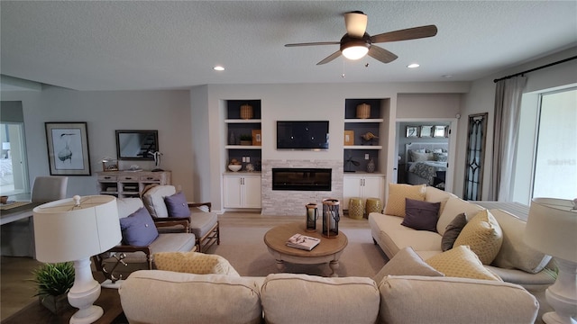 living room featuring light hardwood / wood-style flooring, plenty of natural light, built in features, and a textured ceiling