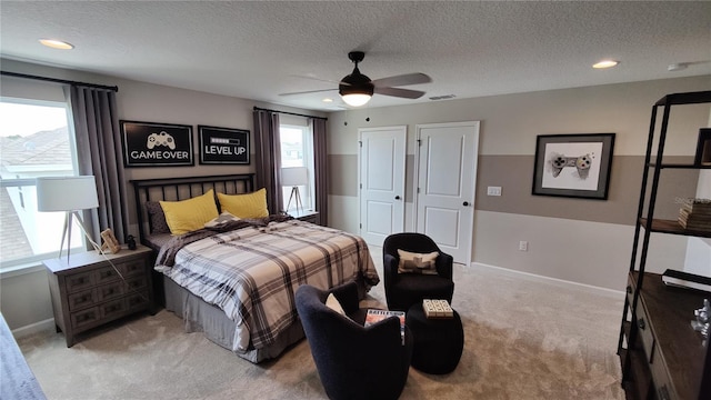 bedroom with multiple closets, a textured ceiling, light colored carpet, and ceiling fan