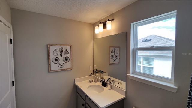 bathroom with vanity, lofted ceiling, and a textured ceiling