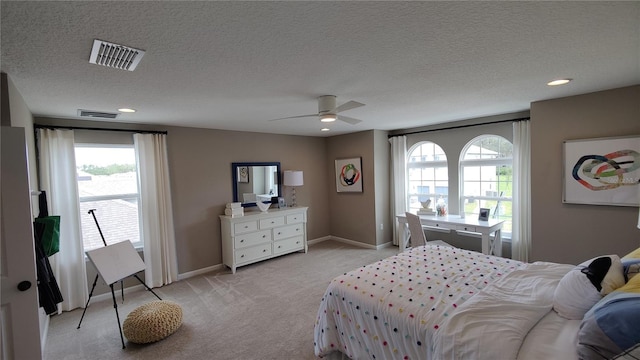 carpeted bedroom with ceiling fan, multiple windows, and a textured ceiling