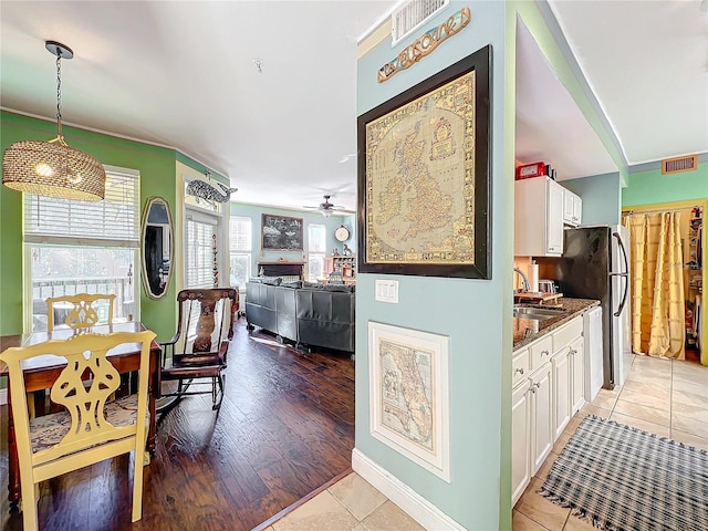 kitchen with pendant lighting, sink, dark stone countertops, light hardwood / wood-style floors, and white cabinets