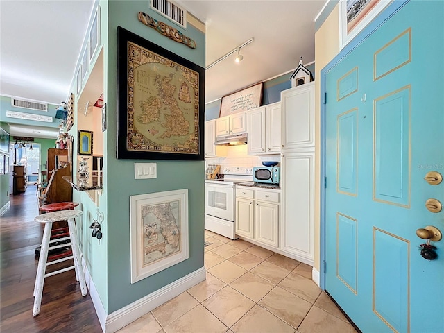 kitchen featuring white cabinets, a kitchen bar, electric range, and backsplash