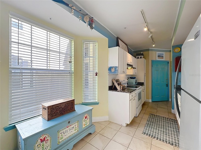 kitchen featuring light tile patterned flooring, rail lighting, dark stone countertops, white appliances, and white cabinets