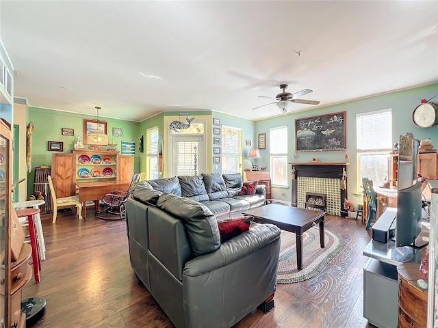 living room featuring ceiling fan, ornamental molding, dark hardwood / wood-style floors, and a tile fireplace