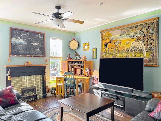 living room with dark wood-type flooring, ceiling fan, a fireplace, and crown molding