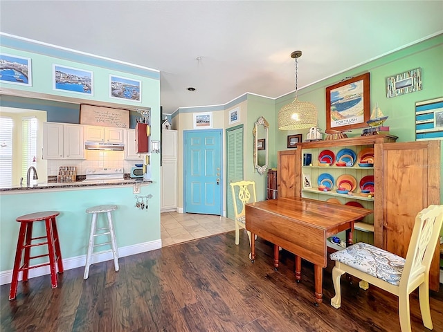 dining room with sink, hardwood / wood-style flooring, and ornamental molding