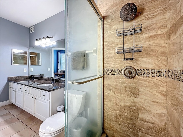 bathroom featuring tile patterned flooring, vanity, tiled shower, and toilet