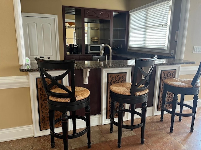 bar with sink and dark brown cabinets