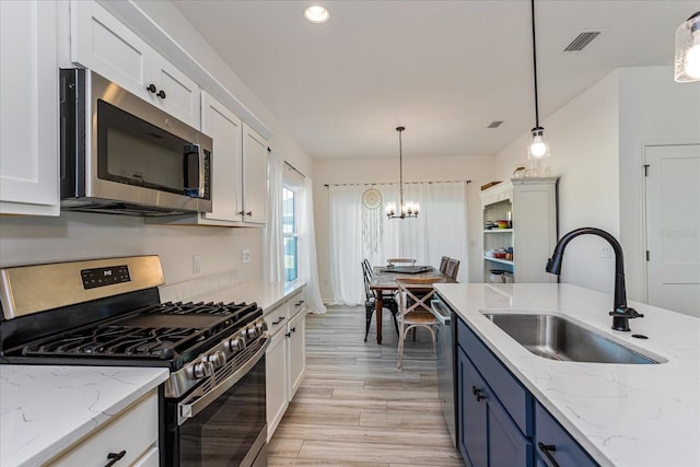 kitchen featuring appliances with stainless steel finishes, pendant lighting, white cabinetry, sink, and blue cabinetry