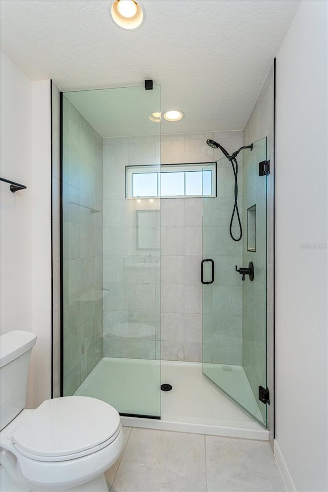 bathroom featuring walk in shower, tile patterned floors, a textured ceiling, and toilet