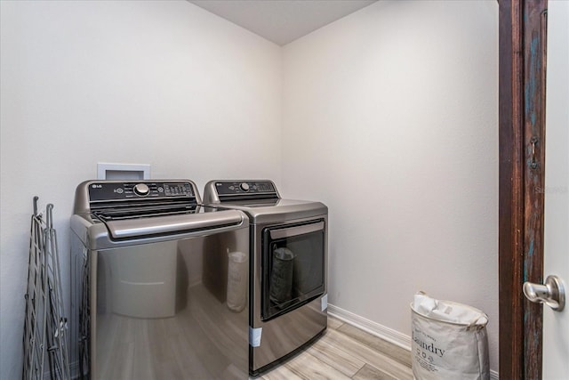 washroom with washer and clothes dryer and light hardwood / wood-style flooring