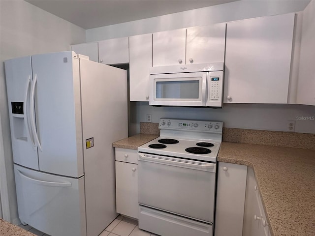 kitchen featuring white cabinetry, light stone countertops, light tile patterned floors, and white appliances