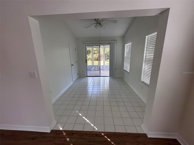 spare room featuring vaulted ceiling, light tile patterned flooring, and ceiling fan