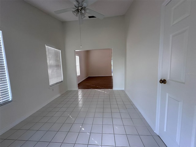 unfurnished room featuring a high ceiling, light tile patterned floors, and ceiling fan