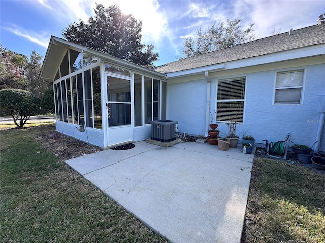 rear view of property with central AC, a sunroom, a patio area, and a lawn