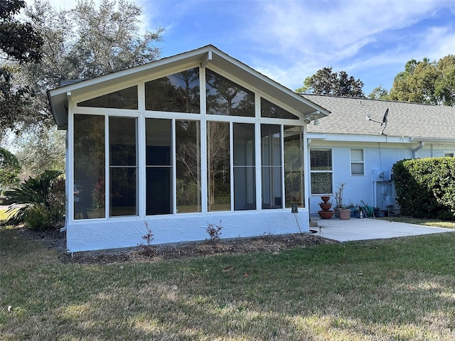 rear view of house featuring a patio, a sunroom, and a lawn