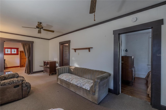 living room featuring ceiling fan, ornamental molding, and carpet