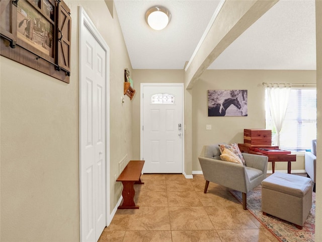 foyer entrance featuring a textured ceiling and light tile patterned flooring