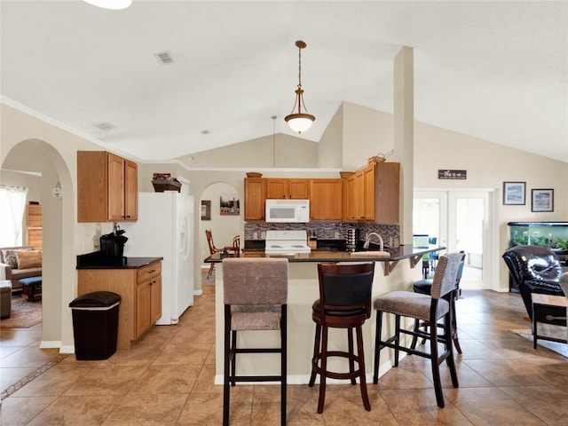 kitchen featuring white appliances, a healthy amount of sunlight, decorative light fixtures, and a kitchen breakfast bar