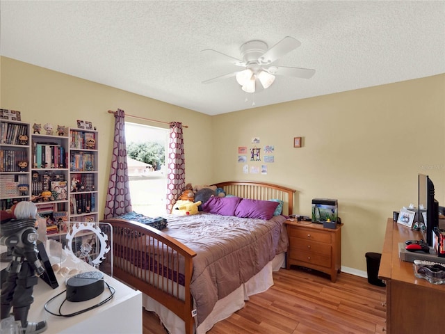 bedroom featuring ceiling fan, light hardwood / wood-style floors, and a textured ceiling