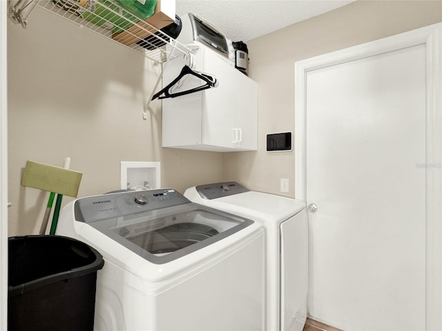 washroom with cabinets, separate washer and dryer, and a textured ceiling