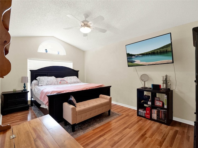 bedroom with lofted ceiling, ceiling fan, wood-type flooring, and a textured ceiling