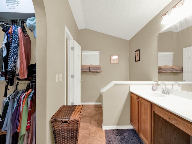 bathroom featuring vanity, vaulted ceiling, tile patterned floors, and a textured ceiling