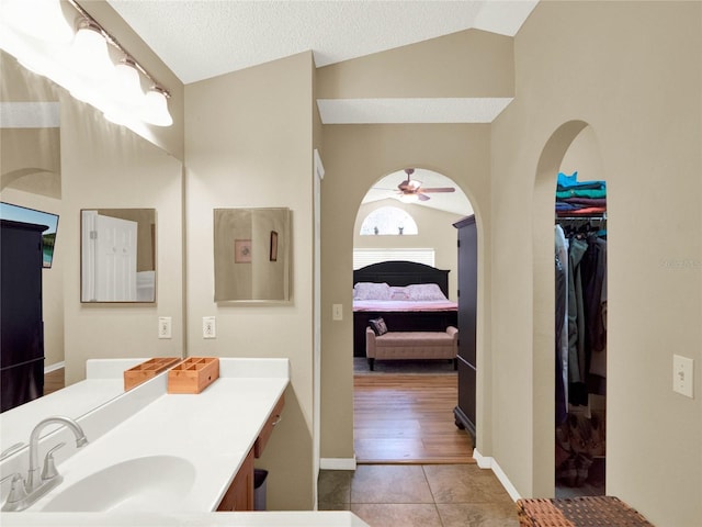 bathroom with tile patterned flooring, vanity, lofted ceiling, and ceiling fan