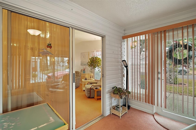 doorway to outside with crown molding, carpet floors, wooden walls, and a textured ceiling