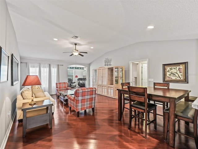 living room with dark wood-type flooring, vaulted ceiling, a textured ceiling, and ceiling fan