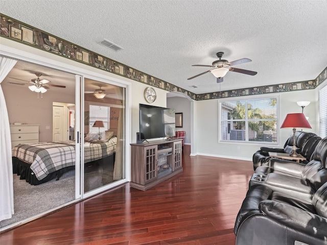 living room with ceiling fan, dark wood-type flooring, and a textured ceiling