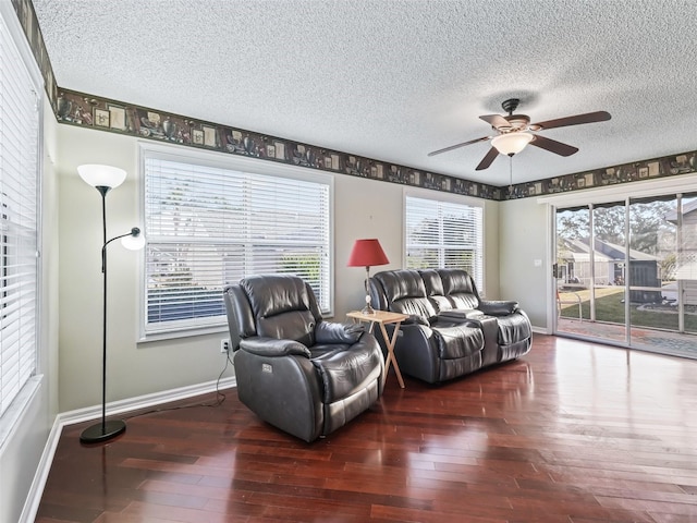 living room with a textured ceiling, dark hardwood / wood-style floors, and ceiling fan