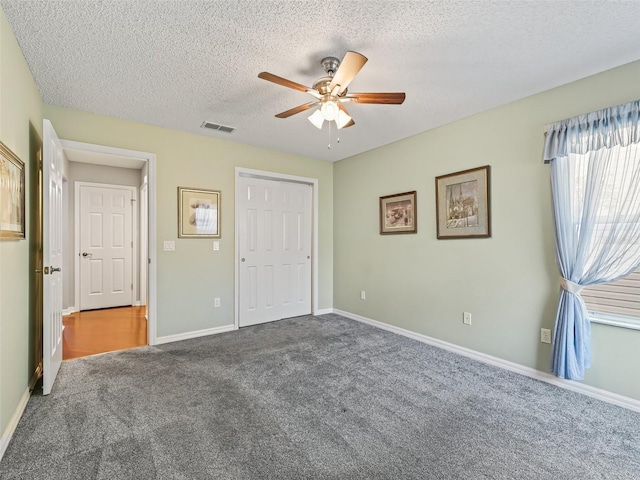 unfurnished bedroom with ceiling fan, carpet, a textured ceiling, and a closet