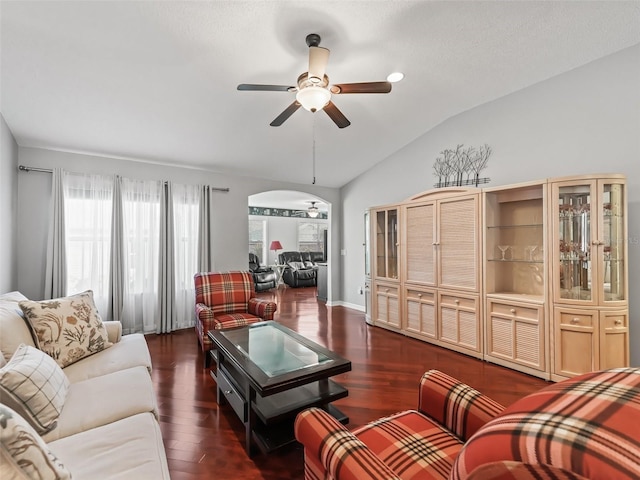 living room with dark wood-type flooring, ceiling fan, and vaulted ceiling