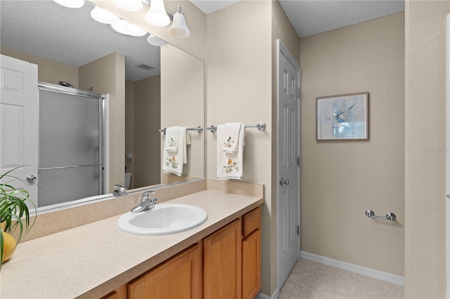 bathroom featuring vanity, tile patterned flooring, a shower with shower door, and a textured ceiling