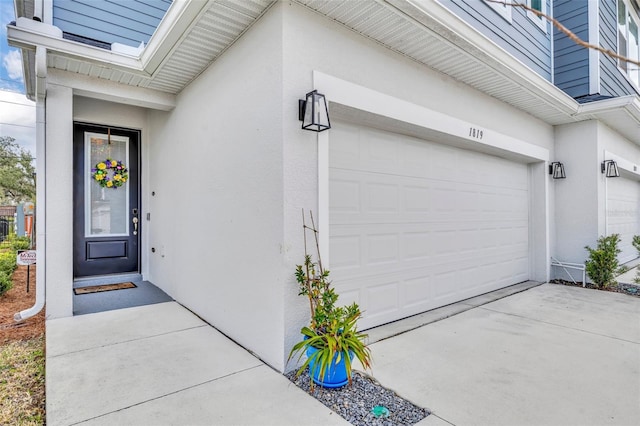 view of exterior entry featuring driveway and stucco siding