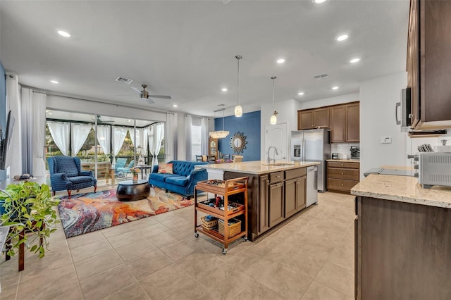 kitchen with a sink, stainless steel appliances, light stone counters, and open floor plan