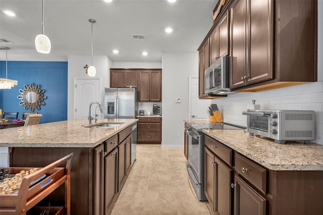 kitchen featuring visible vents, pendant lighting, a sink, appliances with stainless steel finishes, and dark brown cabinets