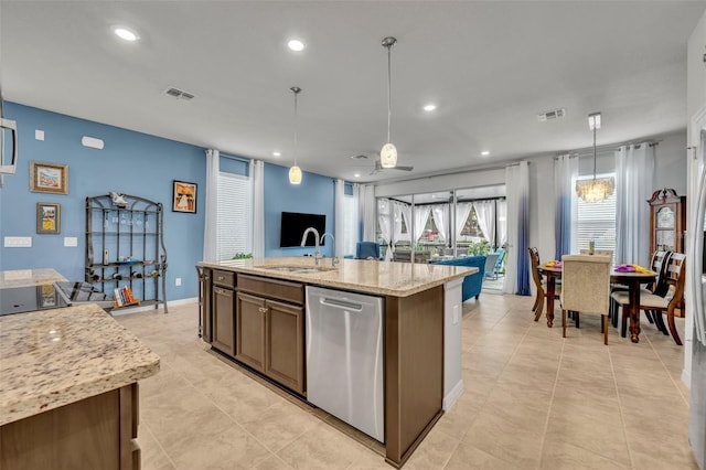 kitchen featuring stainless steel dishwasher, a kitchen island with sink, visible vents, and a sink