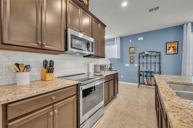 kitchen featuring light stone countertops, baseboards, visible vents, appliances with stainless steel finishes, and backsplash