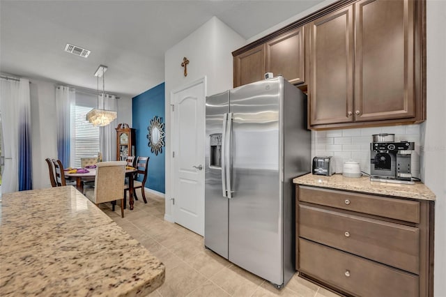 kitchen with tasteful backsplash, visible vents, light stone counters, light tile patterned floors, and stainless steel refrigerator with ice dispenser