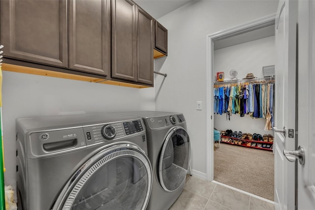 laundry room with light carpet, washer and clothes dryer, cabinet space, light tile patterned flooring, and baseboards