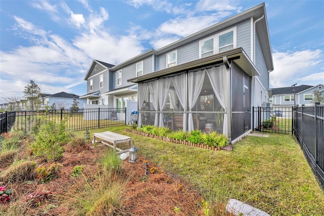 rear view of house featuring a yard, a fenced backyard, a residential view, and a sunroom