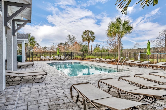 community pool with a patio and fence