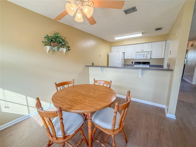 dining room featuring ceiling fan, dark hardwood / wood-style flooring, sink, and a textured ceiling