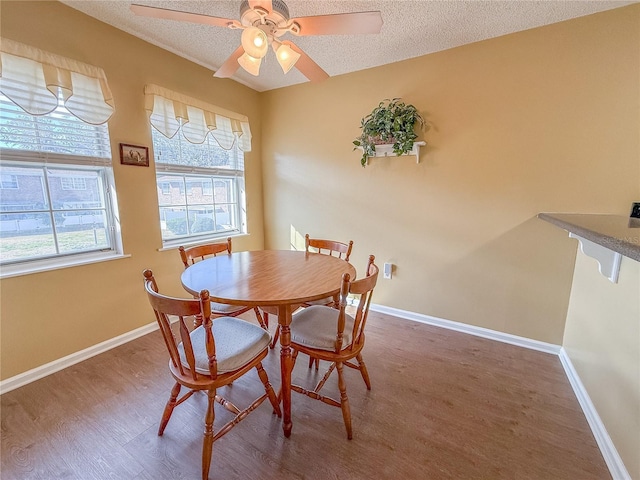 dining space with hardwood / wood-style flooring, ceiling fan, and a textured ceiling