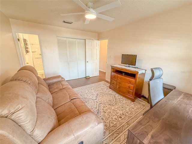 living room with hardwood / wood-style flooring, a textured ceiling, and ceiling fan