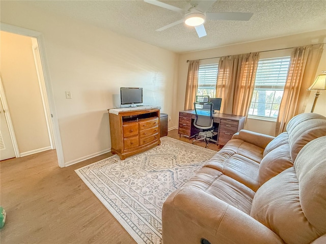 living room featuring a textured ceiling, ceiling fan, and light hardwood / wood-style flooring