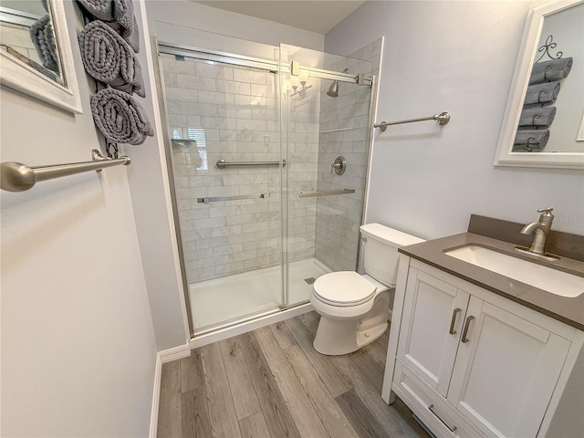 bathroom with wood-type flooring, walk in shower, vanity, and toilet